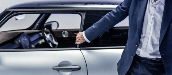 A hand grabbing the handle of a silver car.