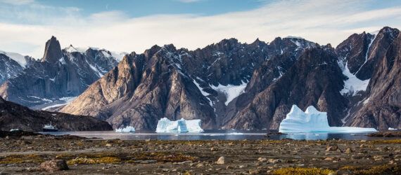 A snowy mountain range with warmer land at the base.
