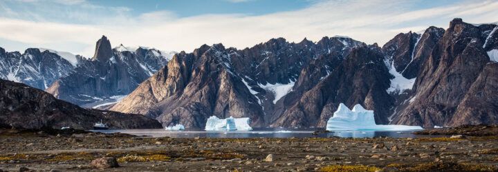 A snowy mountain range with warmer land at the base.