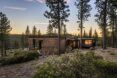 A landscape view of a home with wood siding surrounded by a forest.