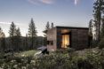 A landscape view of a home with wood siding surrounded by a forest.