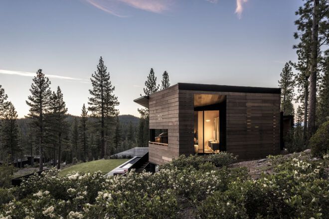 A landscape view of a home with wood siding surrounded by a forest.
