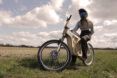 A person in a bike helmet posed on a wooden e-bike.