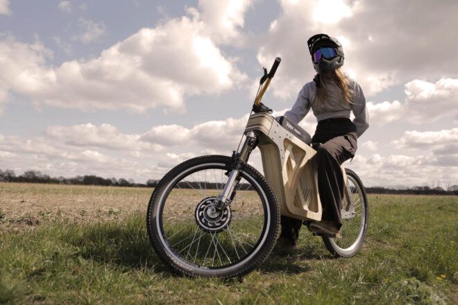 A person in a bike helmet posed on a wooden e-bike.