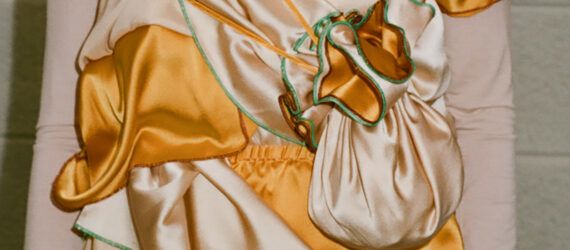 A close-up of the detail on an orange and peach-colored silk dress.