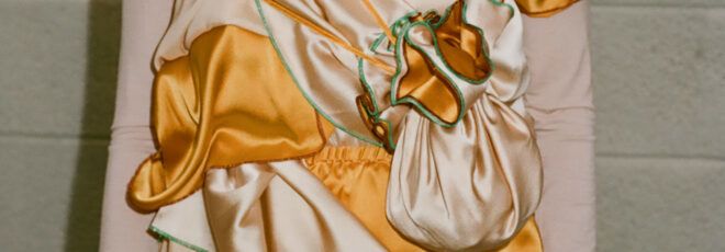 A close-up of the detail on an orange and peach-colored silk dress.