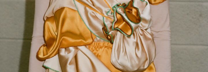 A close-up of the detail on an orange and peach-colored silk dress.