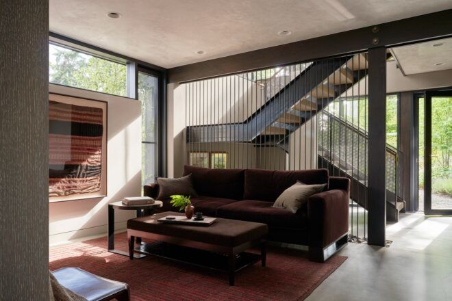 A living room with a red sofa and rug. In the background is a staircase to the second floor.