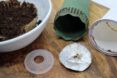 A green cone-like device next to a deconstructed coffee pod.
