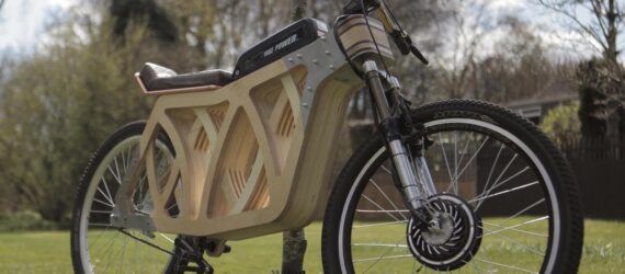 A cropped image of a wooden e-bike on a grassy lawn.