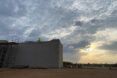 A person standing on top of an in-construction building in the middle of a desert.