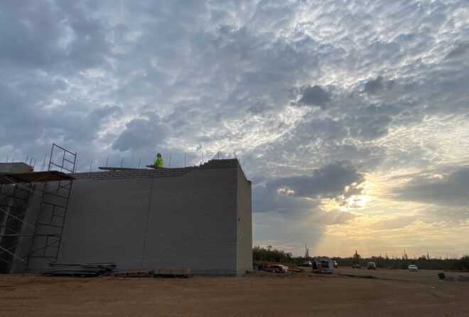 A person standing on top of an in-construction building in the middle of a desert.