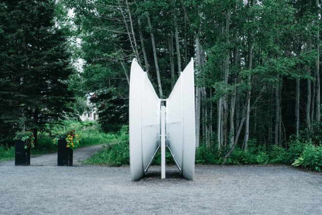A structure that looks like two satellite dishes connected to each other and facing out at a forest.