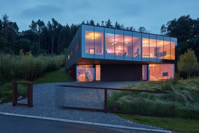 A streetview of a rectangular, two-story home with floor-to-ceiling windows.