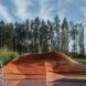 A swimming pool with a wavy, triangular wood structure built over one corner.