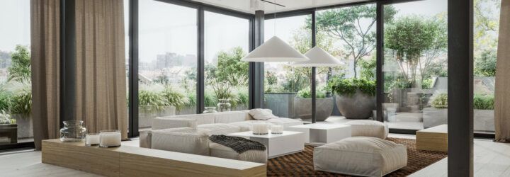 A living room with a white sofa, coffee table and ottoman, surrounded by floor-to-ceiling windows.