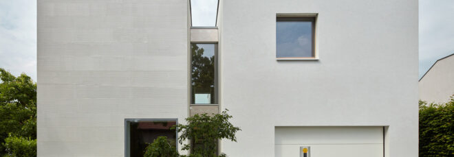 A streetview of the home, showing four white volumes to create two connected towers.