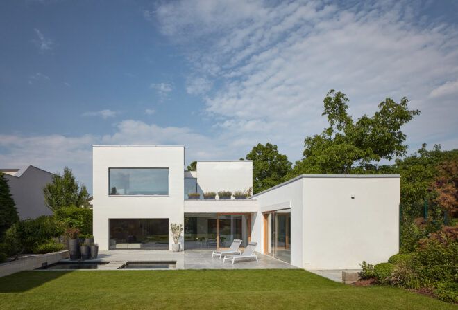 A green backyard sits in front of the back of the home, where a patio sits next to a pool.