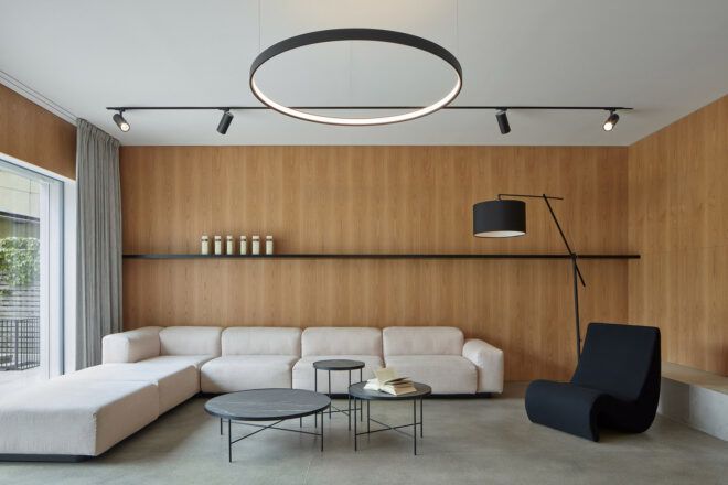 A living room with a white sofa and wood walls. A black armchair sits to the right.