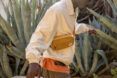 A person wearing a tan bag slung across their body.