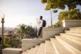 A person wearing a backpack and standing on a set of stairs outdoors.