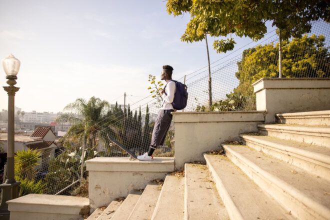 A person wearing a backpack and standing on a set of stairs outdoors.