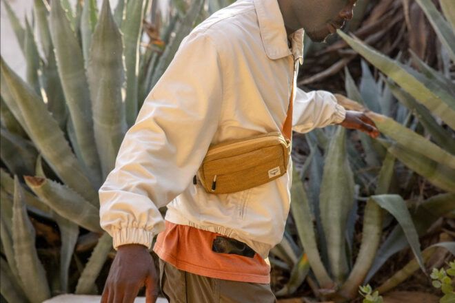A person wearing a tan bag slung across their body.