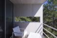 A balcony with a white deck chair overlooking a forest.