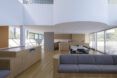 A living room with light-toned wood floors and accents. A gray sofa sits in the middle of the room.
