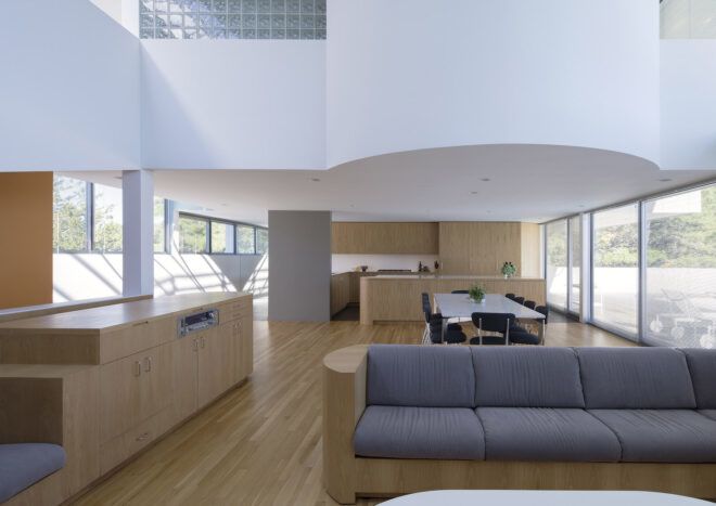 A living room with light-toned wood floors and accents. A gray sofa sits in the middle of the room.