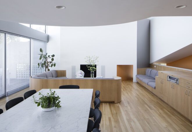 A view of the dining area, where a white table surrounded by black chairs overlooks the living room.
