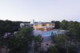 A view of the entire residence, showing a pool in front of a long, rectangular two-level home.