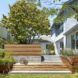 A green yard sits in front of wood and concrete steps that lead up to a house.