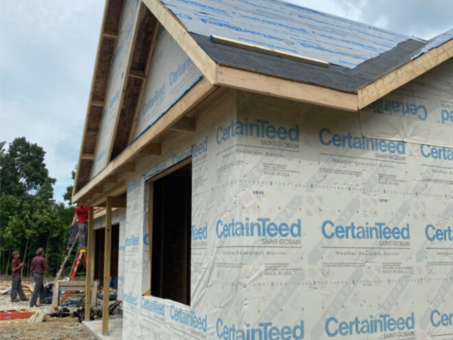Side facade of house under construction with a single window