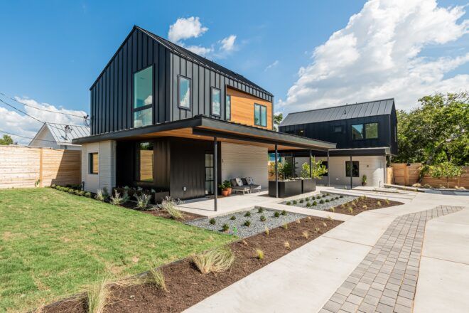 A walkway leading up to a two-story home with a covered patio and attached yard.