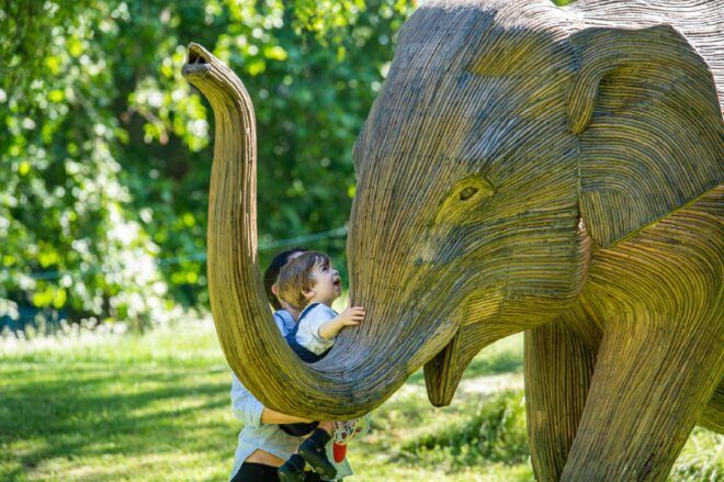 A child hugging the elephant sculpture's snout