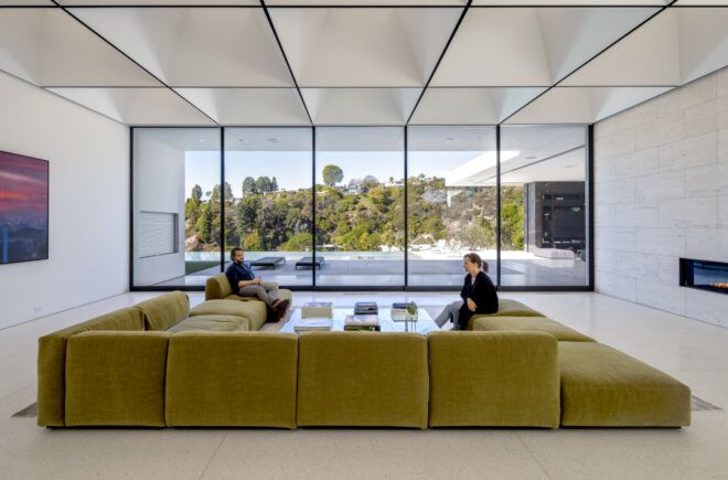 Couches arranged in a horseshoe under a grid of skylights with a view to the hills.