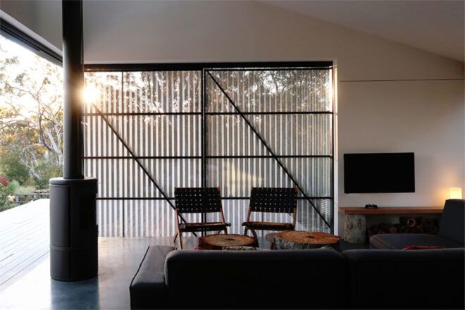 To the left, a glass door overlooking the veranda. To the right, a living room with a sofa and two chairs.