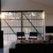 To the left, a glass door overlooking the veranda. To the right, a living room with a sofa and two chairs.