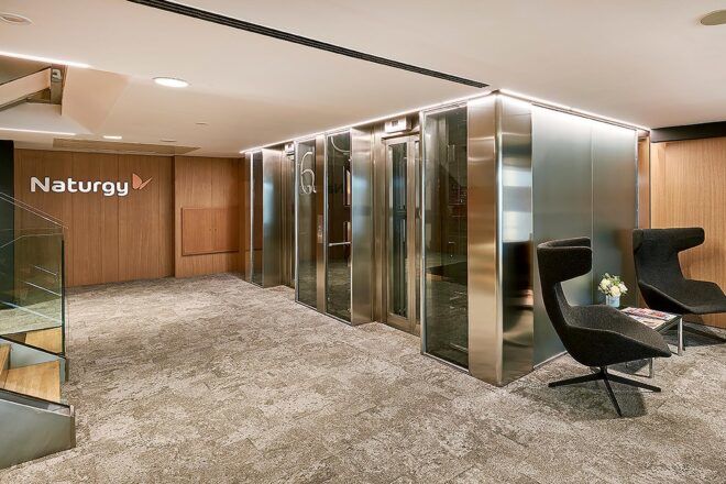 A neutral-toned office space with chrome detail near meeting rooms to the right.