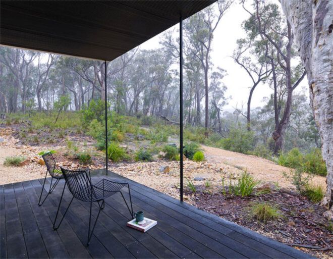 A wire chair on a patio overlooking a forest.