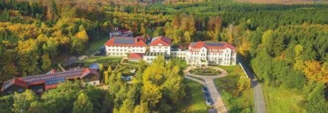 An overhead view of a large hotel with a white facade and red roof.