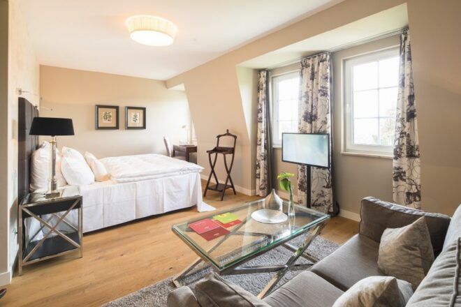 A bedroom with a bed, sofa, coffee table and beige walls.