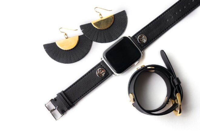 A pair of black semi-circle earrings, a black watch and a black bracelet against a white background.