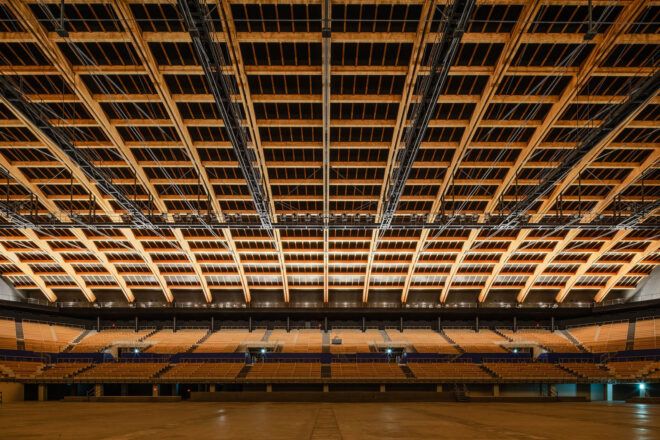 A basketball court with wood bleachers and ceiling.