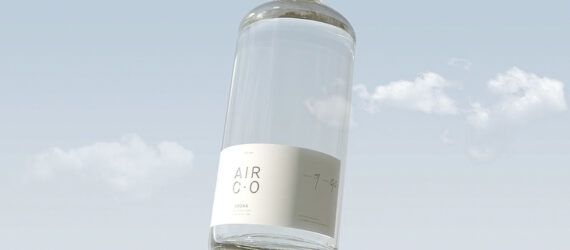 A clear bottle with a white lable against a blue sky background.