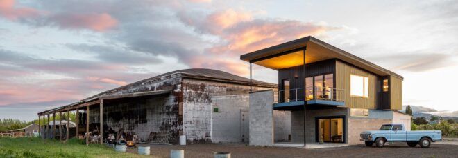 An old barn building next to a modern home.