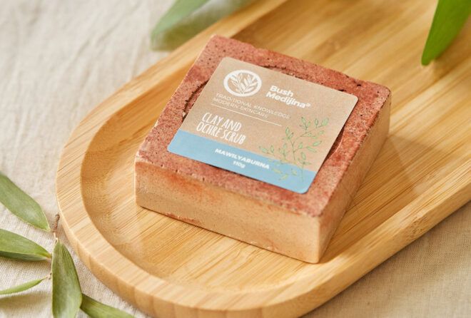 An orange-pink bar of soap on a wood dish.