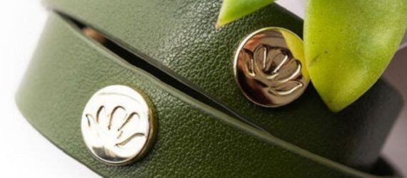 A close-up of two green plant-leather bracelets with metal buttons on them.