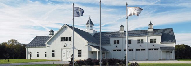 A landscape shot of a white building with three flagpoles in front of it.